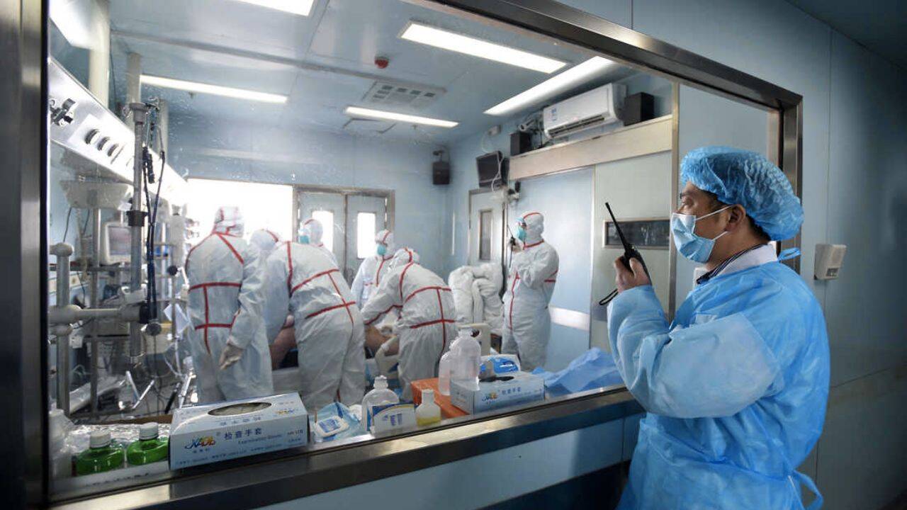 mai multe persoane imbracate in combinezoane intr-o camera de spital