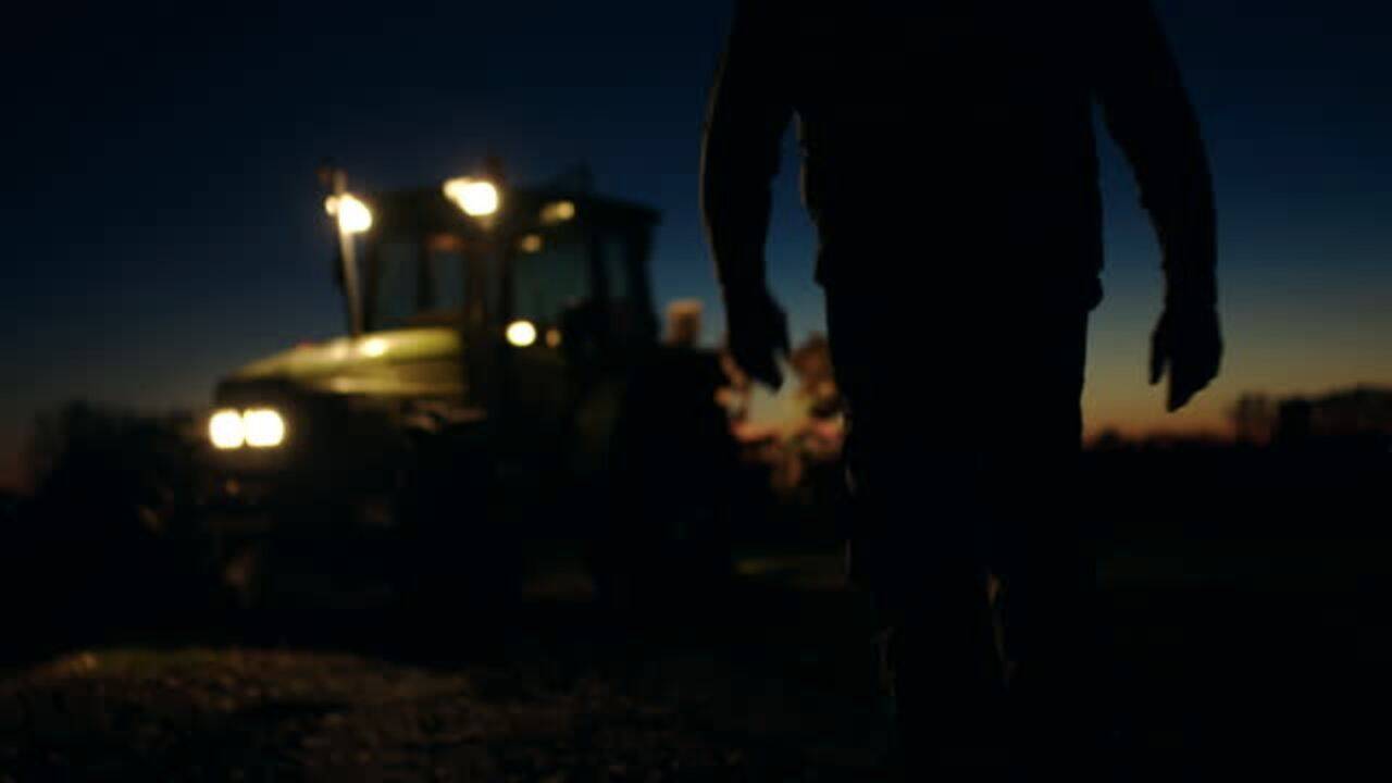 o silueta care se indreapta spre un tractor noaptea